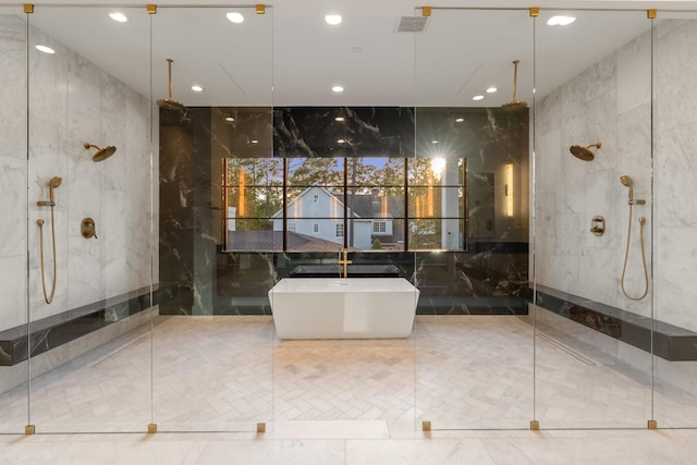 bathroom with a marble finish shower, tile walls, a freestanding tub, and recessed lighting