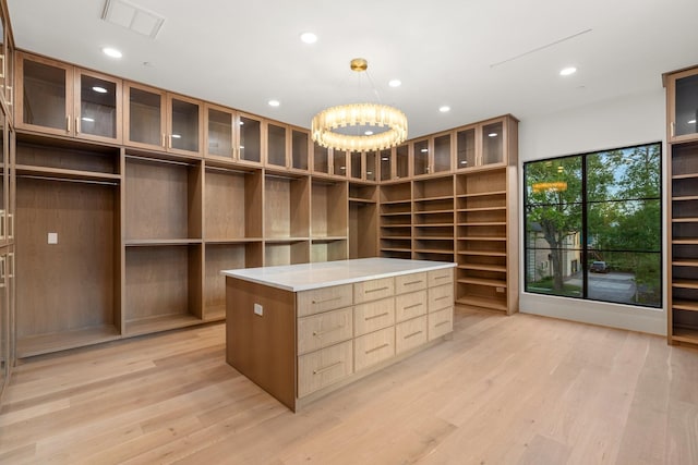 walk in closet featuring light wood-type flooring and a chandelier
