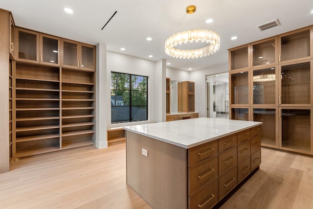walk in closet with light wood-type flooring and a chandelier