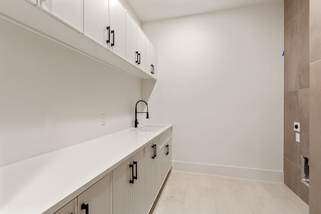 washroom featuring electric dryer hookup, cabinet space, and baseboards