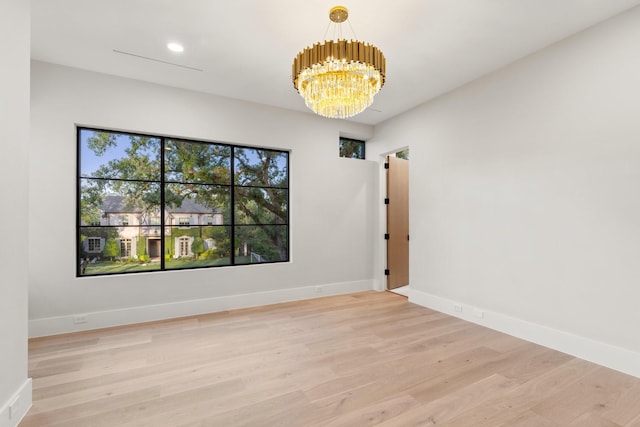 spare room featuring a chandelier, light wood-style flooring, baseboards, and recessed lighting