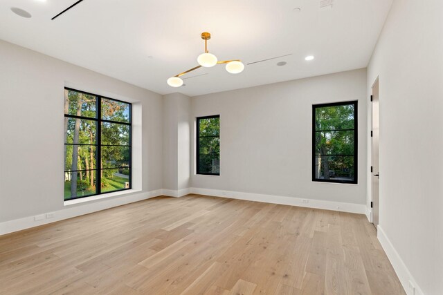 empty room featuring light wood-type flooring, baseboards, and recessed lighting