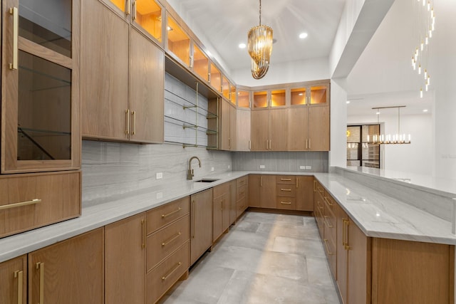 kitchen with a chandelier, a sink, decorative backsplash, and light stone countertops
