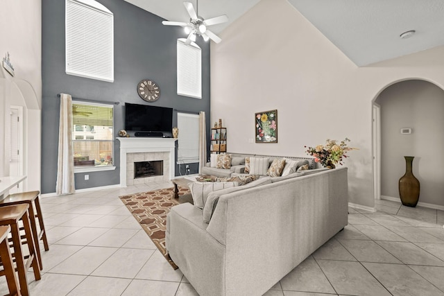 7103 Uther Ct, Spring, TX 77379 - living room with high vaulted ceiling, light tile patterned floors, a ceiling fan, arched walkways, and a tiled fireplace