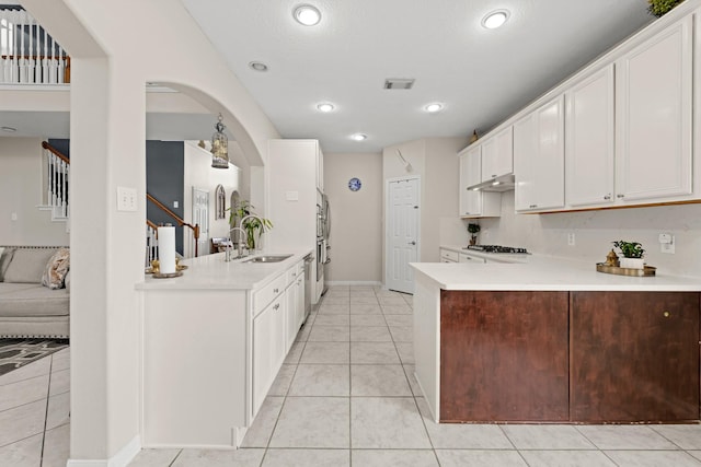 7103 Uther Ct, Spring, TX 77379 - kitchen featuring a peninsula, light countertops, arched walkways, under cabinet range hood, and recessed lighting