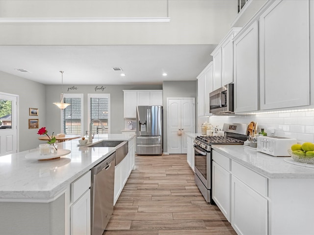 711 Summer Trace Ln, Richmond, TX 77406 - kitchen with stainless steel appliances, light wood finished floors, white cabinets, backsplash, and recessed lighting