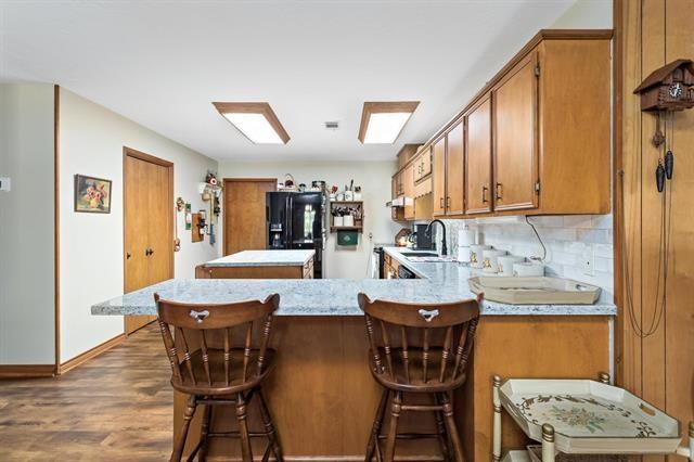527 E Walton Rd, Lumberton, TX 77657 - kitchen with black fridge, brown cabinetry, light countertops, a sink, and dark wood-type flooring