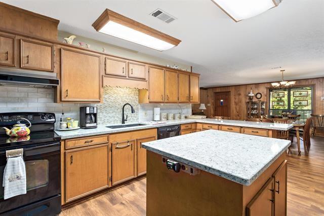 527 E Walton Rd, Lumberton, TX 77657 - kitchen featuring black appliances, under cabinet range hood, a sink, a peninsula, and light wood finished floors