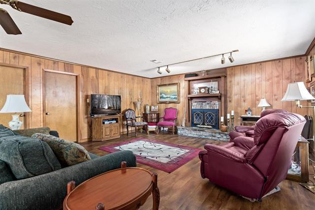 527 E Walton Rd, Lumberton, TX 77657 - living room featuring wooden walls, a ceiling fan, rail lighting, and wood finished floors