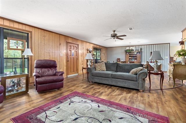 527 E Walton Rd, Lumberton, TX 77657 - living area with a ceiling fan, wood finished floors, a textured ceiling, and wooden walls