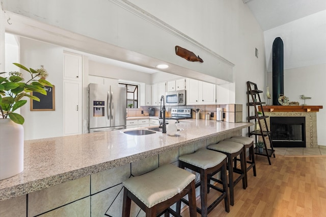 211 4th St, Dickinson, TX 77539 - kitchen featuring stainless steel appliances, a peninsula, high vaulted ceiling, white cabinets, and light stone countertops