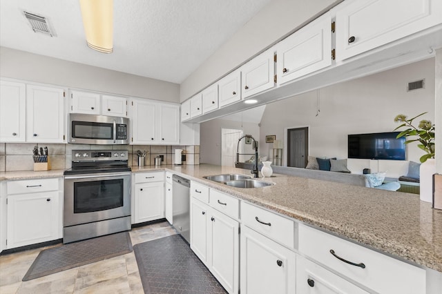 211 4th St, Dickinson, TX 77539 - kitchen featuring stainless steel appliances, a sink, white cabinets, and backsplash