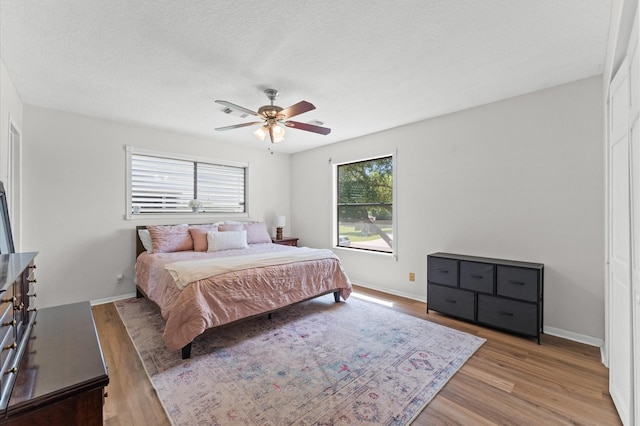 211 4th St, Dickinson, TX 77539 - bedroom featuring light wood finished floors, ceiling fan, baseboards, and a textured ceiling