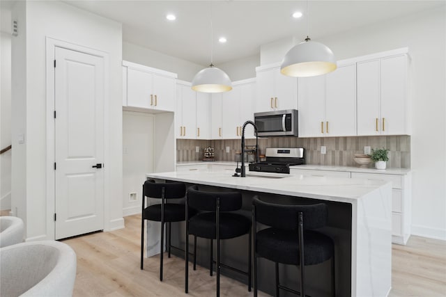 3731 Lydia St, Houston, TX 77021 - kitchen featuring appliances with stainless steel finishes, decorative backsplash, light wood-style flooring, a breakfast bar area, and light countertops
