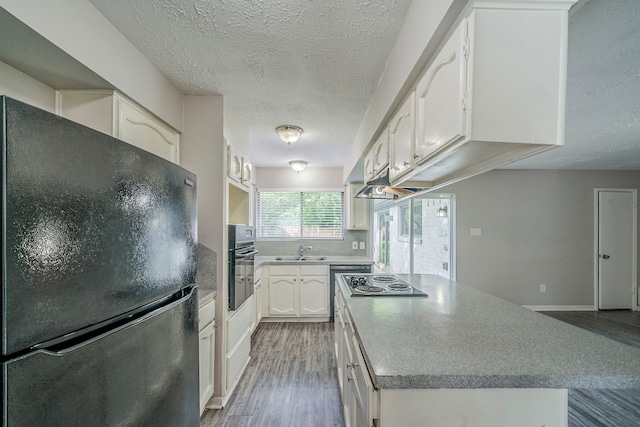7218 Winding Trace Dr, Houston, TX 77086 - kitchen with black appliances, wood finished floors, a textured ceiling, a sink, and white cabinets