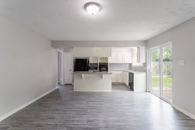 7218 Winding Trace Dr, Houston, TX 77086 - kitchen with black appliances, a textured ceiling, dark wood-style flooring, white cabinetry, and a kitchen island