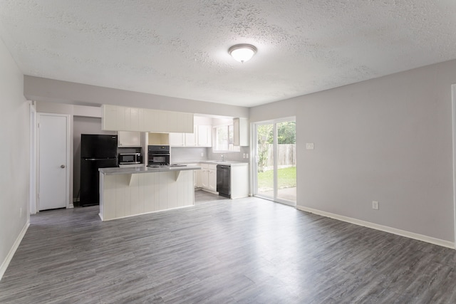 7218 Winding Trace Dr, Houston, TX 77086 - kitchen with black appliances, a textured ceiling, open floor plan, wood finished floors, and a center island