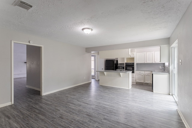 7218 Winding Trace Dr, Houston, TX 77086 - kitchen with a sink, a textured ceiling, dark wood-style floors, open floor plan, and white cabinets