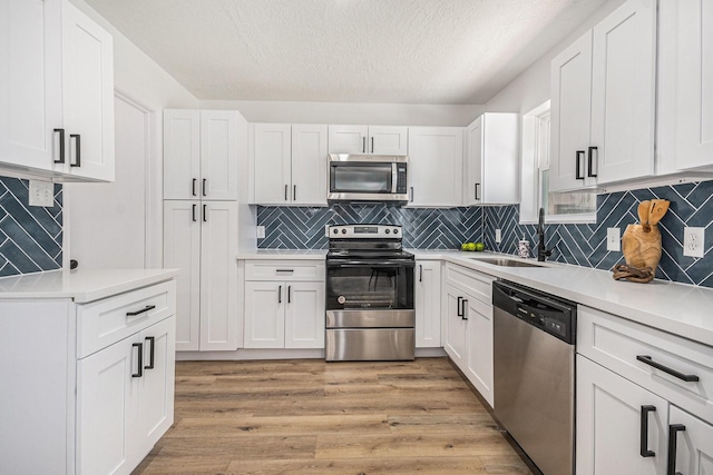 763 Voyager Dr, Houston, TX 77062 - kitchen featuring stainless steel appliances, a textured ceiling, white cabinetry, light countertops, and a sink