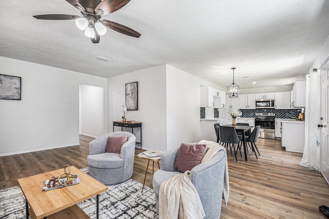 763 Voyager Dr, Houston, TX 77062 - living room with wood finished floors, ceiling fan, a chandelier, a textured ceiling, and baseboards