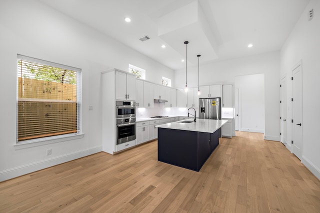 1435 Laird St, Houston, TX 77008 - kitchen featuring stainless steel appliances, a sink, light countertops, light wood-style floors, and a towering ceiling