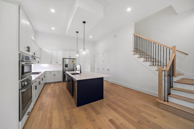 1435 Laird St, Houston, TX 77008 - kitchen with appliances with stainless steel finishes, light countertops, light wood finished floors, hanging light fixtures, and white cabinetry