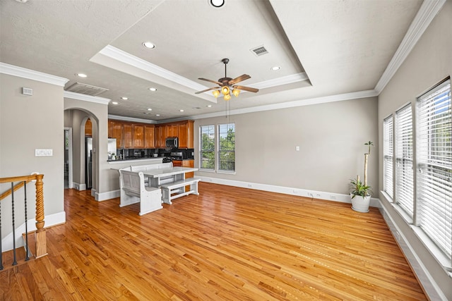 1380 Studer St, Houston, TX 77007 - kitchen featuring stainless steel microwave, arched walkways, light wood-style flooring, baseboards, and a raised ceiling