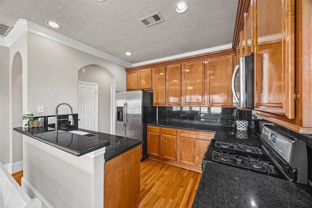 1380 Studer St, Houston, TX 77007 - kitchen with appliances with stainless steel finishes, arched walkways, a sink, crown molding, and light wood-style floors