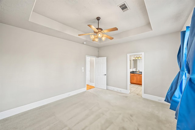 1380 Studer St, Houston, TX 77007 - unfurnished bedroom featuring a tray ceiling, baseboards, light carpet, connected bathroom, and a ceiling fan