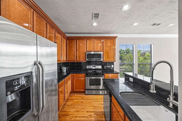 1380 Studer St, Houston, TX 77007 - kitchen featuring appliances with stainless steel finishes, a sink, crown molding, light wood-type flooring, and decorative backsplash