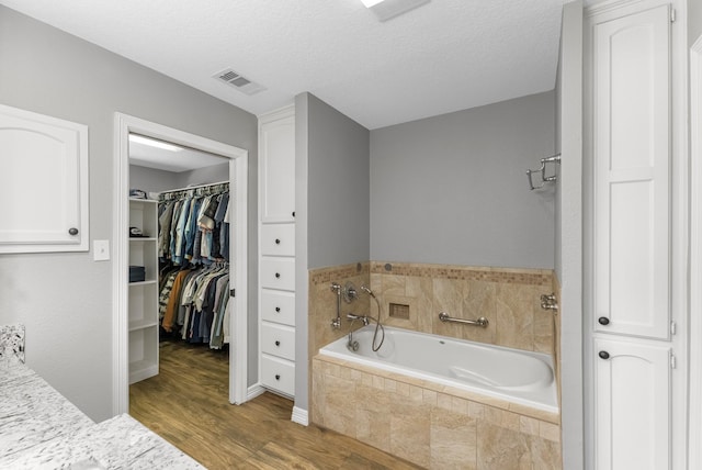 16610 Meadow Ln Unit Cr438, Danbury, TX 77534 - full bathroom with wood finished floors, a garden tub, a textured ceiling, and a spacious closet