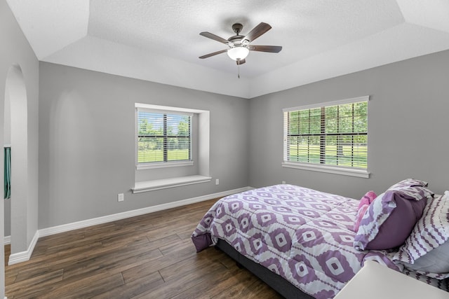 16610 Meadow Ln Unit Cr438, Danbury, TX 77534 - bedroom featuring multiple windows, wood finished floors, a raised ceiling, arched walkways, and a textured ceiling