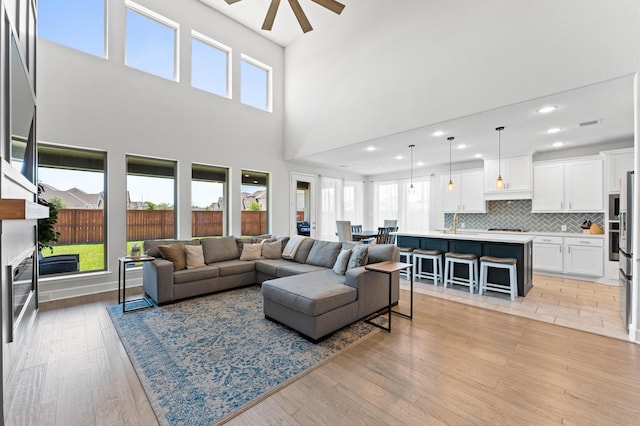 2006 Green Haven Ct, Missouri City, TX 77459 - living area featuring ceiling fan, light wood finished floors, a towering ceiling, a fireplace, and recessed lighting