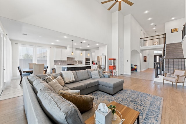 2006 Green Haven Ct, Missouri City, TX 77459 - living room with arched walkways, a ceiling fan, stairs, light wood-type flooring, and a towering ceiling