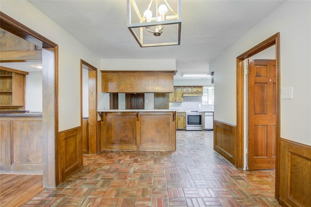 506 Windsor Glen Dr, Katy, TX 77450 - kitchen featuring stainless steel range with electric cooktop, wainscoting, a chandelier, brick flooring, and wooden walls