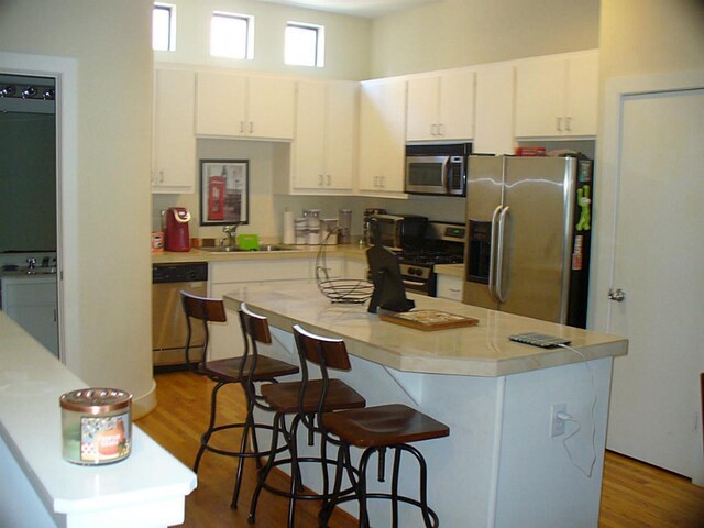 3501 Link Valley Dr Unit 1004, Houston, TX 77025 - kitchen featuring stainless steel appliances, a sink, white cabinets, a kitchen bar, and light countertops
