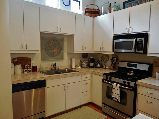 3501 Link Valley Dr Unit 1004, Houston, TX 77025 - kitchen with appliances with stainless steel finishes, light countertops, a sink, light wood-type flooring, and white cabinets