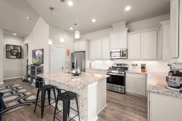 255 S Spotted Fern Dr, Montgomery, TX 77316 - kitchen with appliances with stainless steel finishes, tasteful backsplash, light wood-style flooring, an island with sink, and recessed lighting