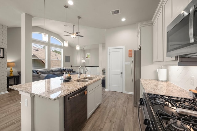 255 S Spotted Fern Dr, Montgomery, TX 77316 - kitchen with stainless steel appliances, a sink, light wood-type flooring, an island with sink, and lofted ceiling