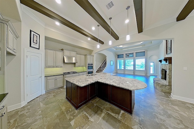 2308 Ellis Park Ln, Conroe, TX 77304 - kitchen featuring under cabinet range hood, baseboards, arched walkways, stone tile floors, and open floor plan