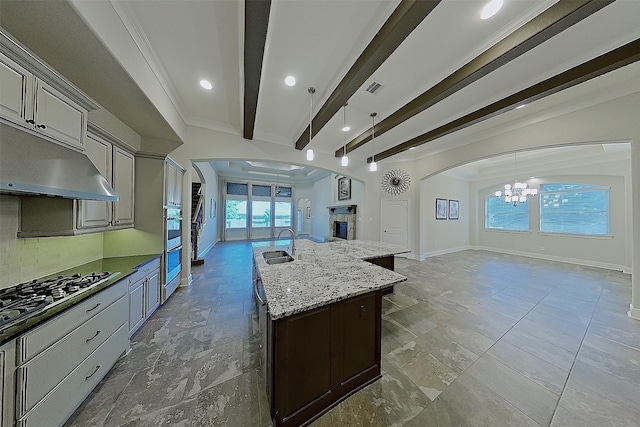 2308 Ellis Park Ln, Conroe, TX 77304 - kitchen with open floor plan, a chandelier, arched walkways, a sink, and beamed ceiling