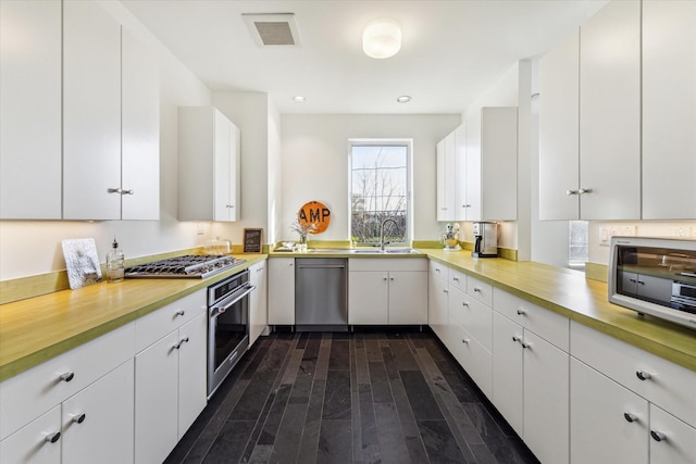 1851 Lexington St, Houston, TX 77098 - kitchen featuring stainless steel appliances, dark wood finished floors, a sink, light countertops, and white cabinets