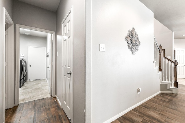 hallway featuring dark wood finished floors, washer / clothes dryer, stairway, and baseboards