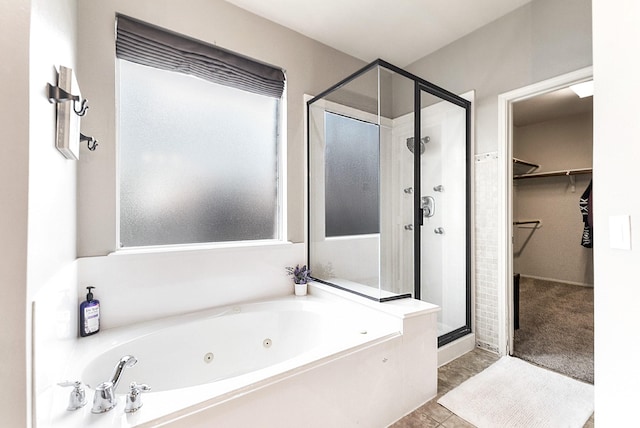 bathroom with a stall shower, a tub with jets, and a spacious closet