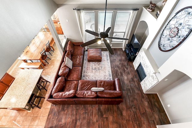 living room with a fireplace, wood finished floors, a ceiling fan, and baseboards