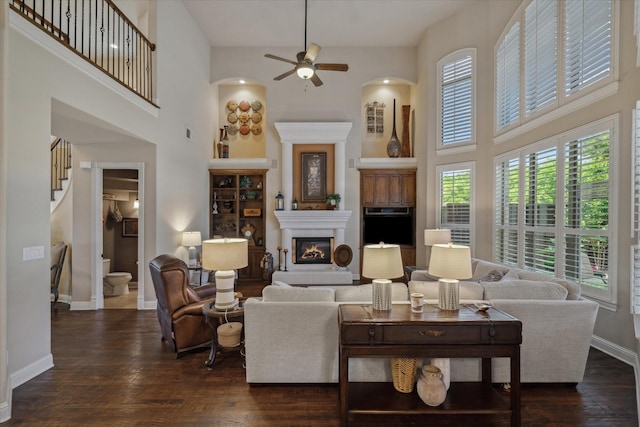 401 Bastrop Dr, Allen, TX 75013 - living area featuring a towering ceiling, dark wood-type flooring, ceiling fan, baseboards, and a glass covered fireplace