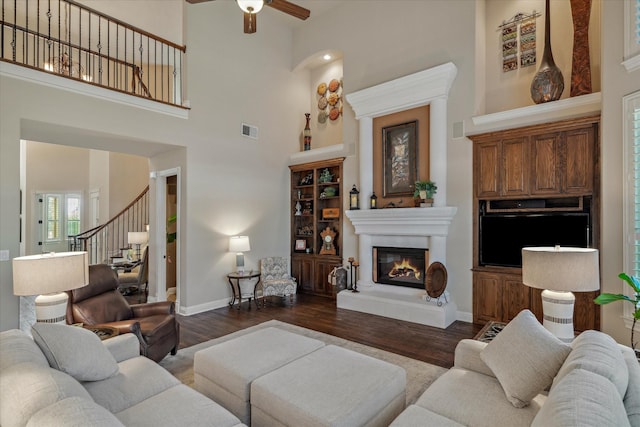 401 Bastrop Dr, Allen, TX 75013 - living area featuring ceiling fan, stairs, dark wood-style floors, a glass covered fireplace, and a towering ceiling