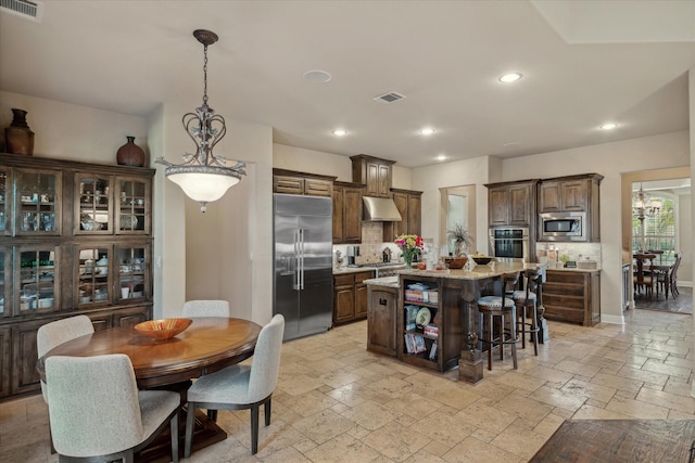 401 Bastrop Dr, Allen, TX 75013 - kitchen with built in appliances, backsplash, under cabinet range hood, stone tile flooring, and a center island
