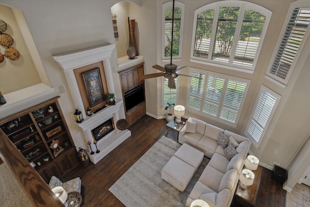 401 Bastrop Dr, Allen, TX 75013 - living area featuring a glass covered fireplace, wood finished floors, a ceiling fan, baseboards, and a towering ceiling