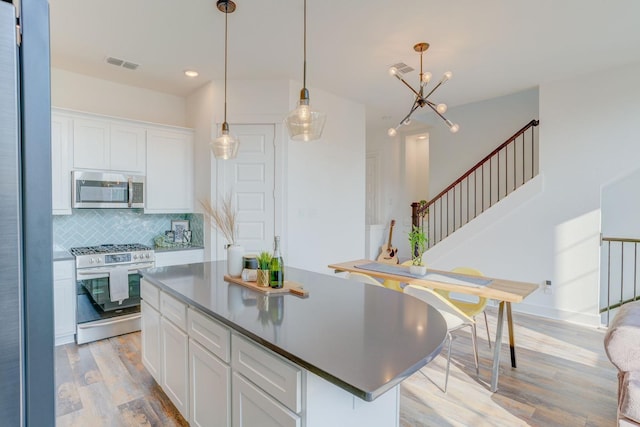 10920 Keaton Landing Dr, Houston, TX 77043 - kitchen with stainless steel appliances, light wood-style flooring, white cabinetry, backsplash, and recessed lighting